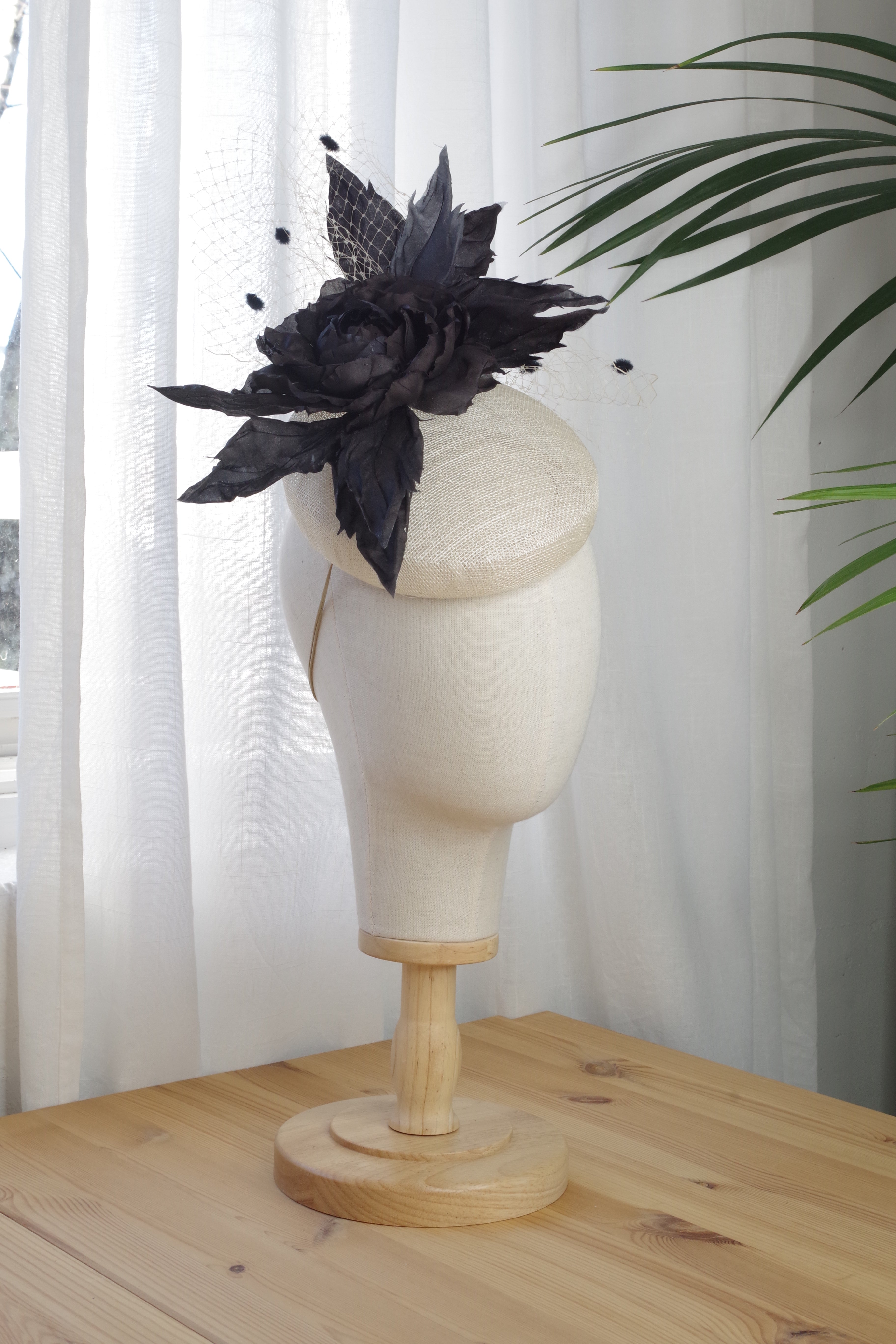 Side view of the handcrafted ivory sinamay fascinator by MICHAETT with a handmade black silk flower.