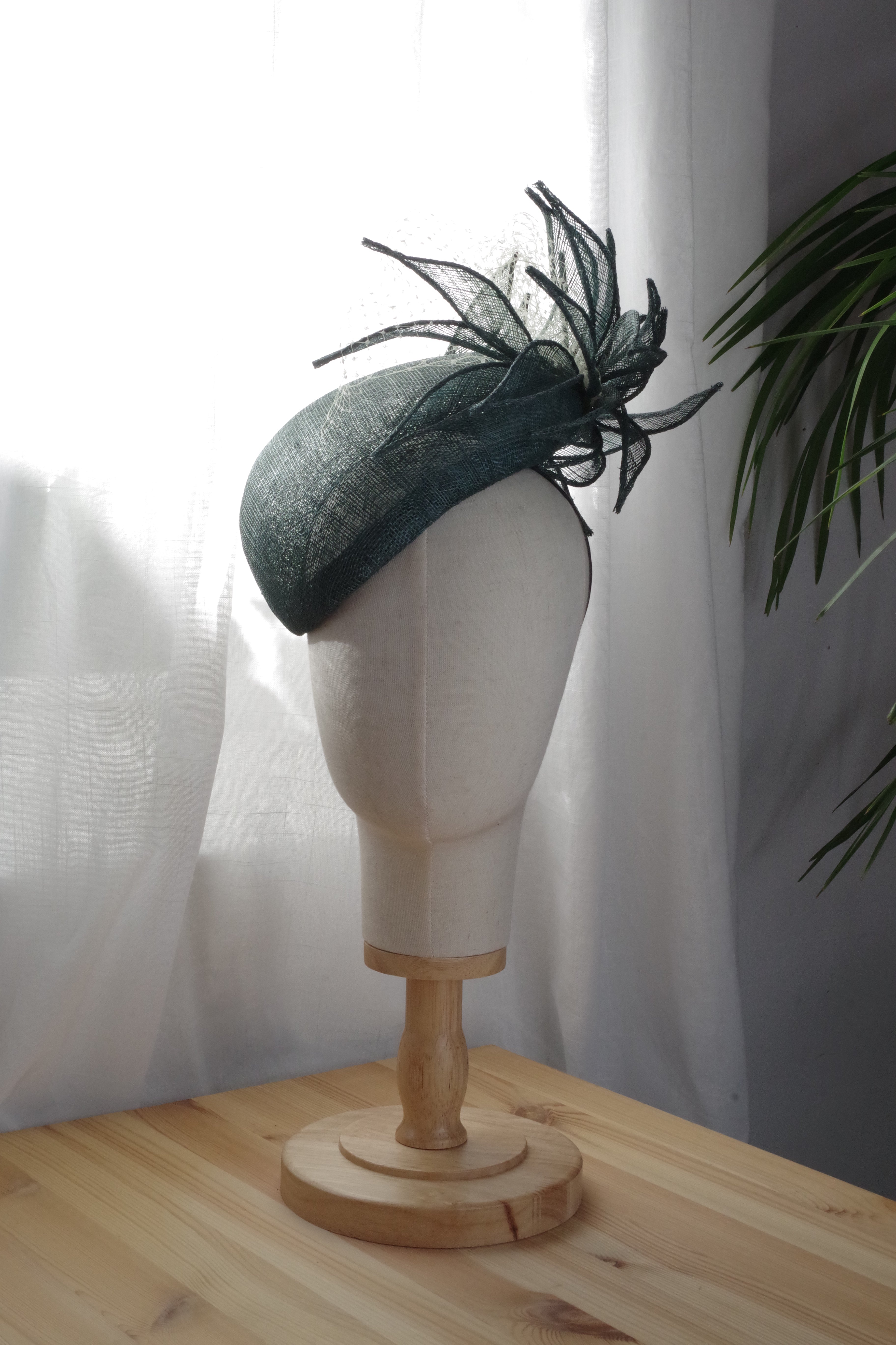 Handcrafted green sinamay cocktail hat by MICHAETT featuring sculptural sinamay foliage, a soft green veil and an elegant asymmetrical silhouette, designed for race days, weddings and special occasions.