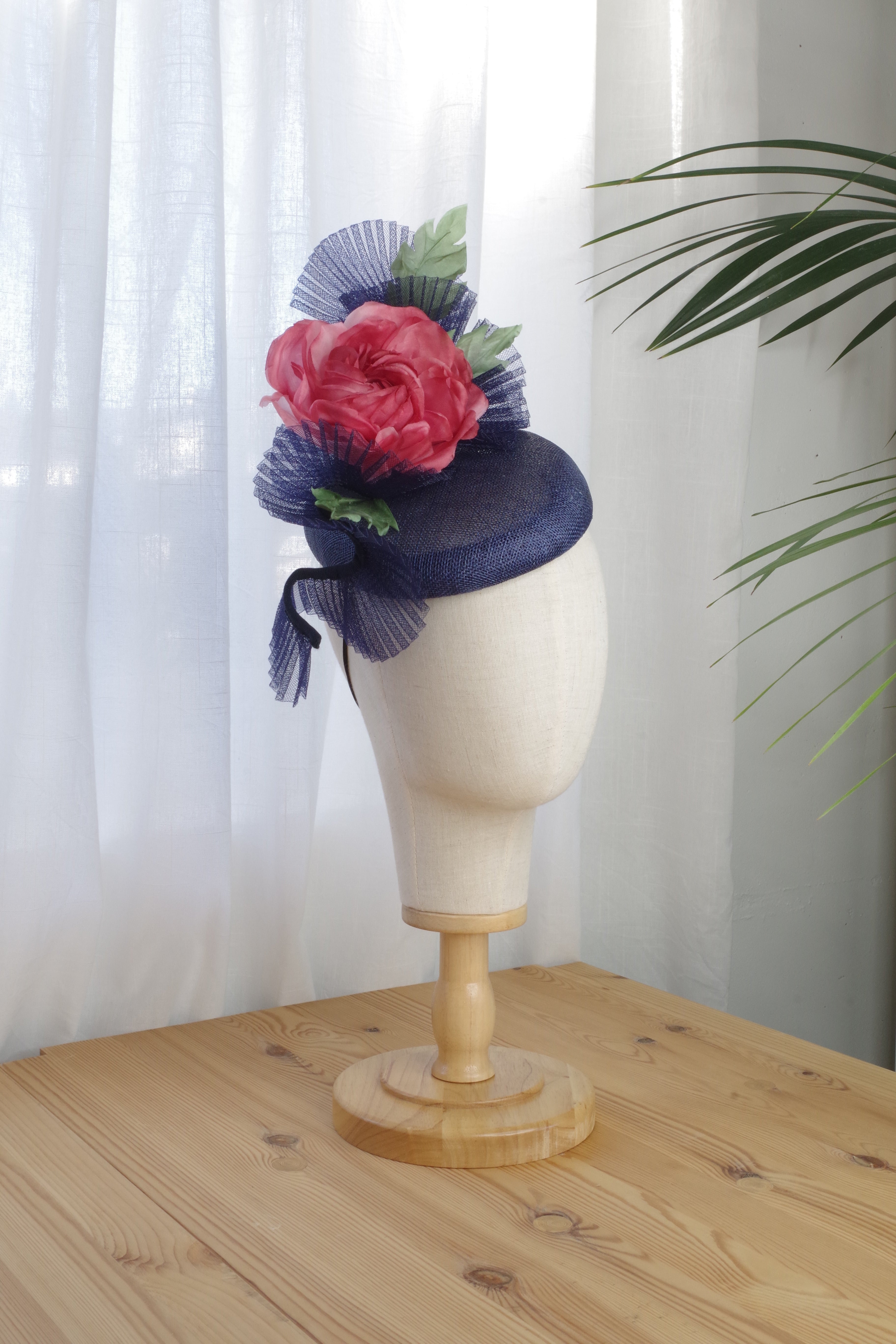 Side view of handcrafted navy sinamay cocktail hat with a coral silk flower by MICHAETT