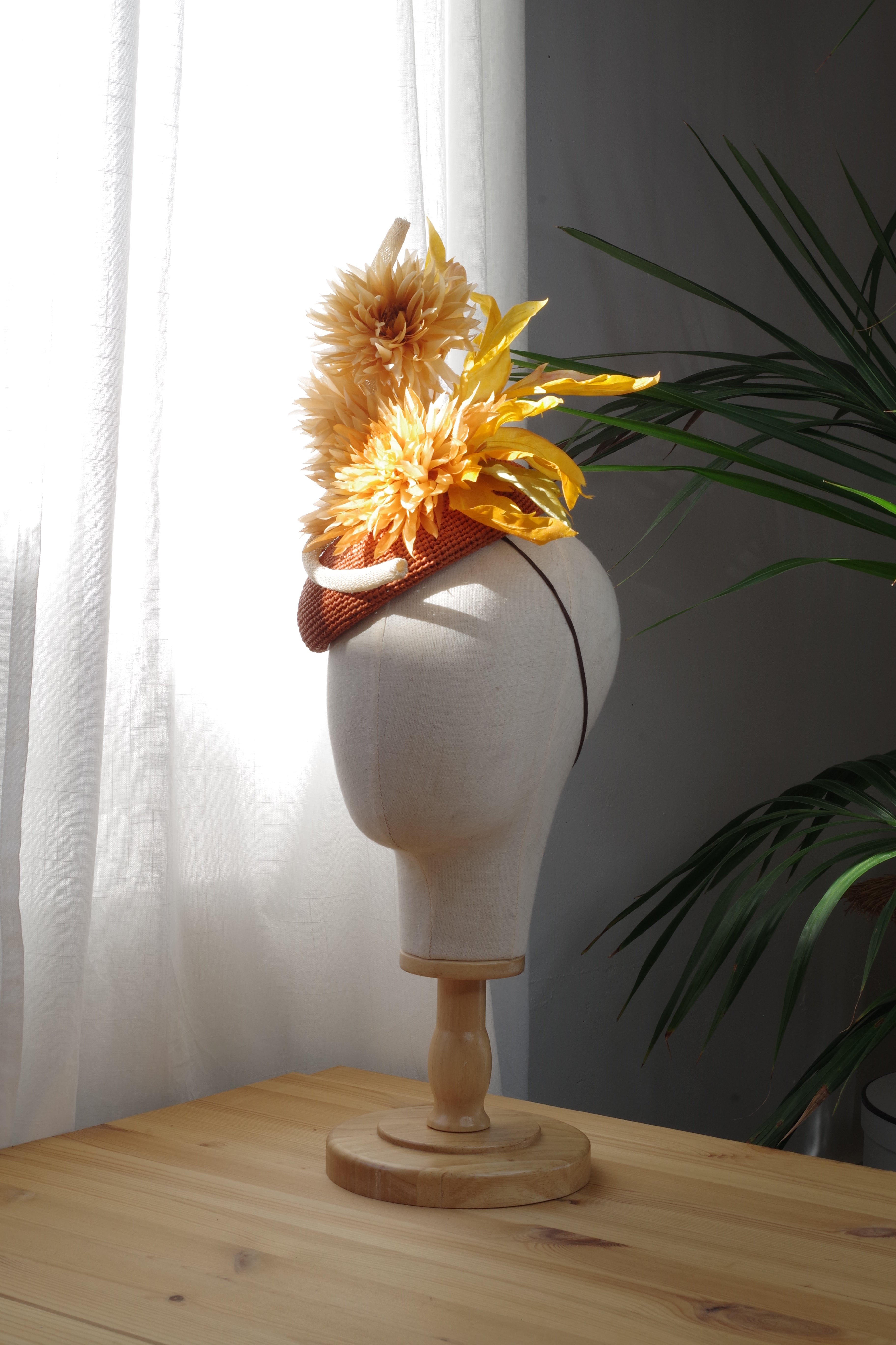 Side view of the Golden Dahlia handcrafted raffia cocktail hat by MICHAETT, showcasing layered golden silk flowers, sculptural foliage and the elegant asymmetrical silhouette.
