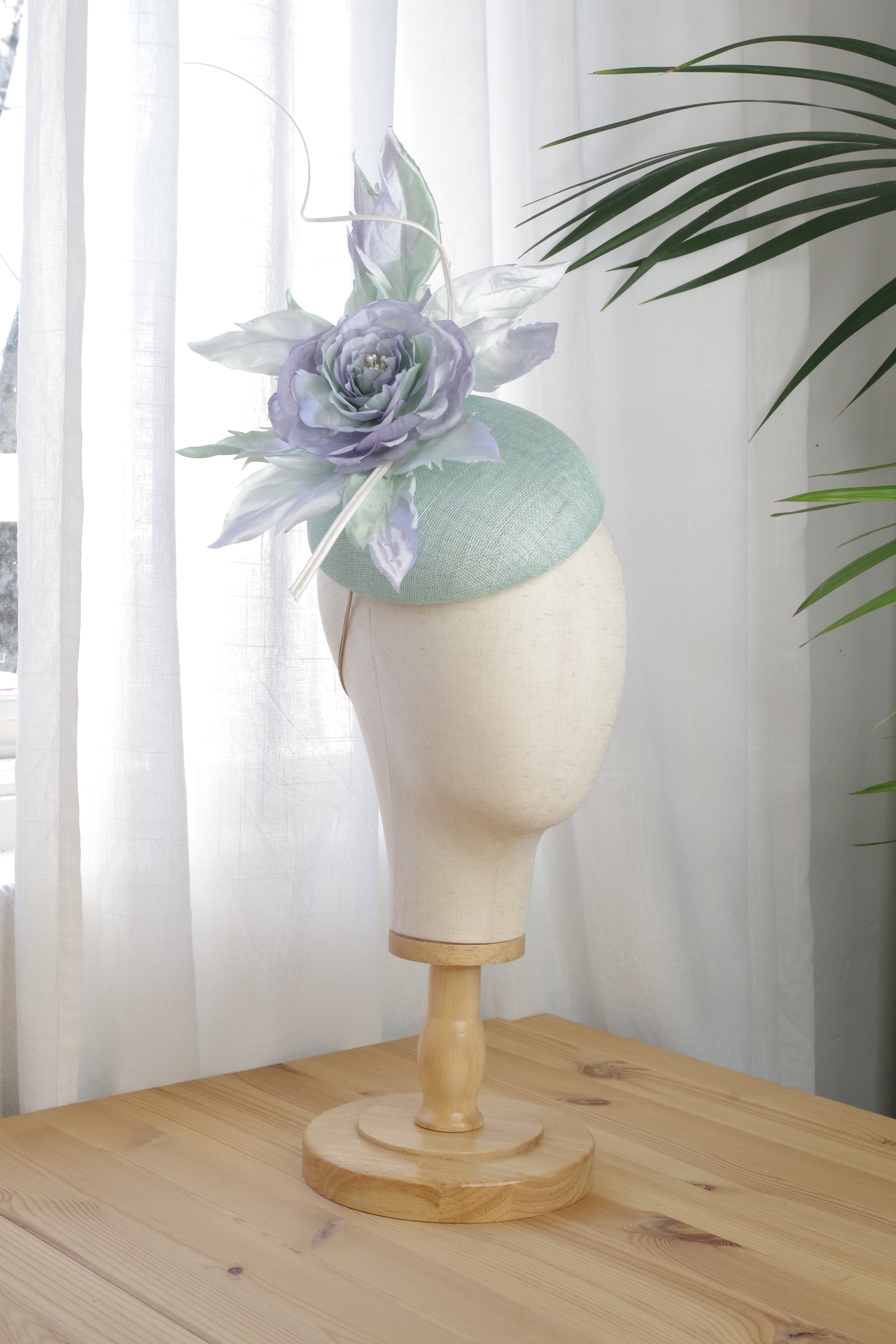 Side view of the handcrafted mint sinamay cocktail hat by MICHAETT showcasing the handmade satin silk flower and silk leaves. 