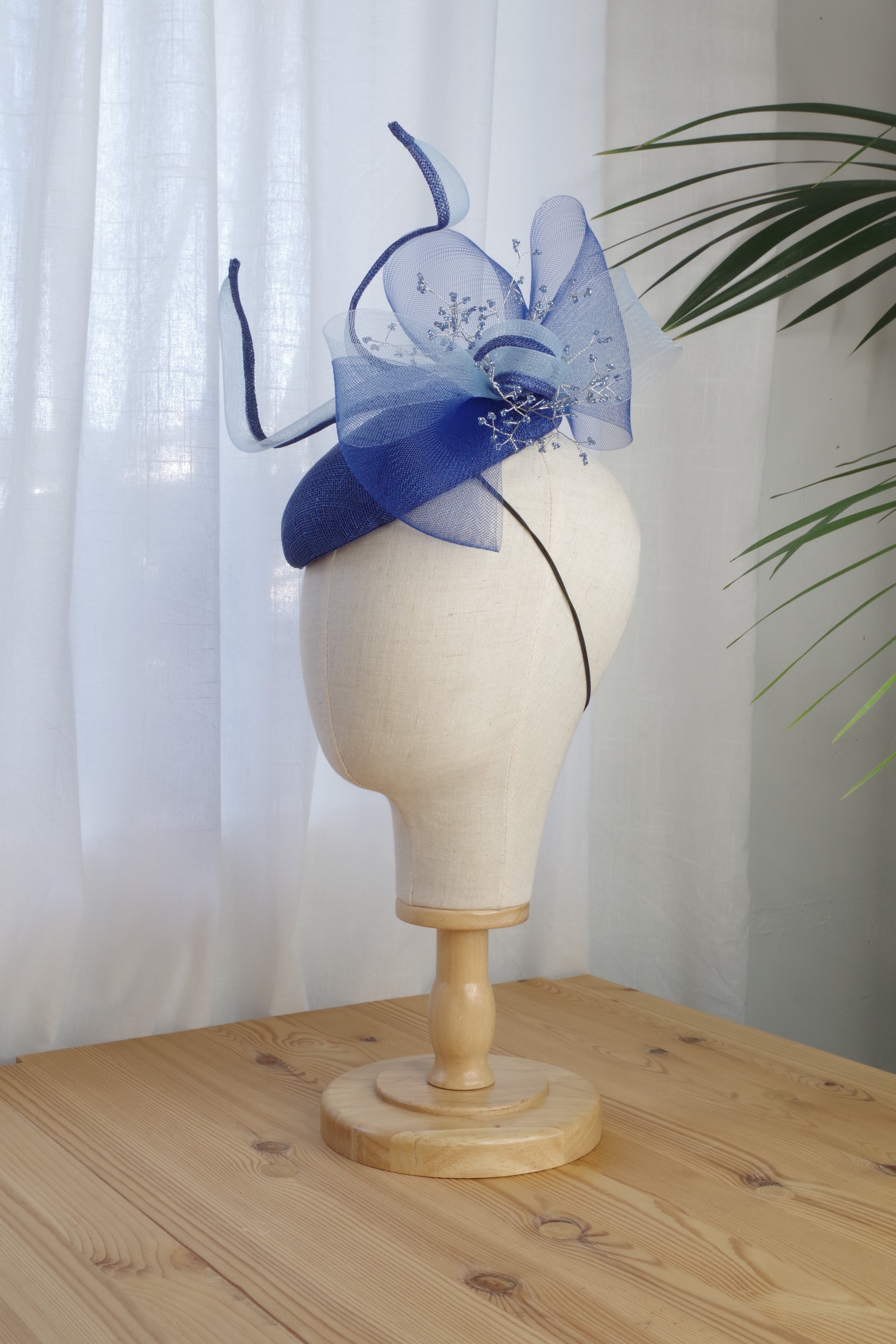 Side view of Sapphire Whirl navy sinamay cocktail hat with sculptural loops and beaded detailing by MICHAETT